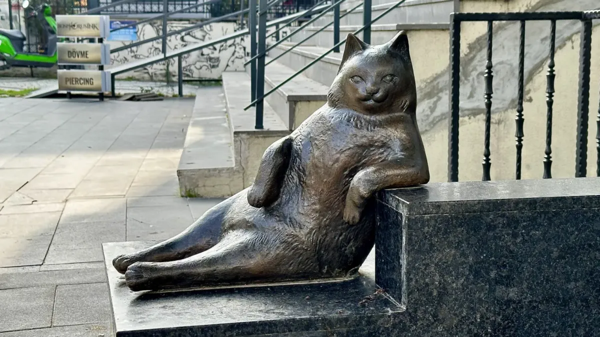 Estatua de bronce de Tombili, un gato rechoncho en pose recostada, sobre una acera de Kadıköy, Estambul