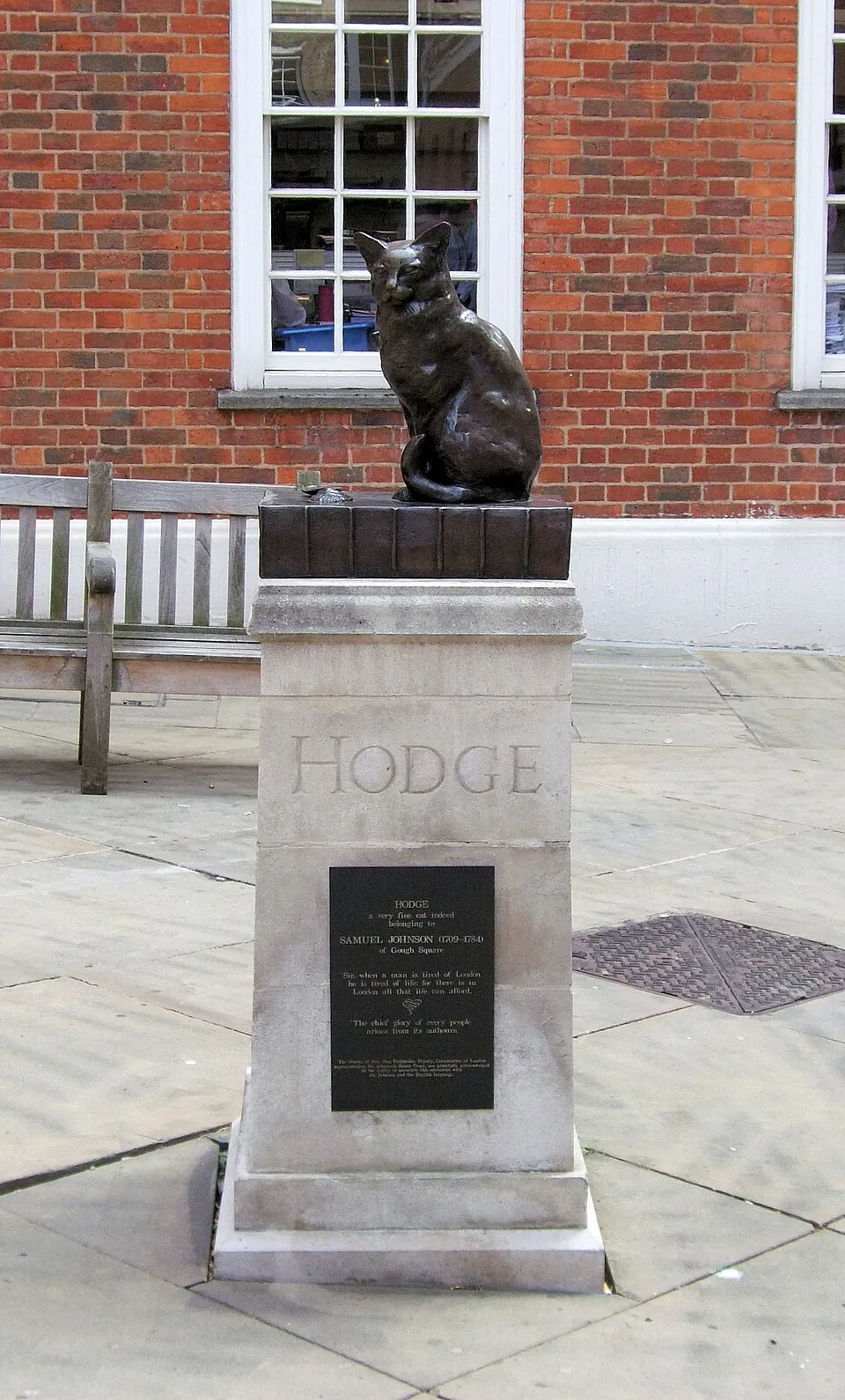 Estatua de bronce de un gato sentado sobre un libro, en una plaza de Londres